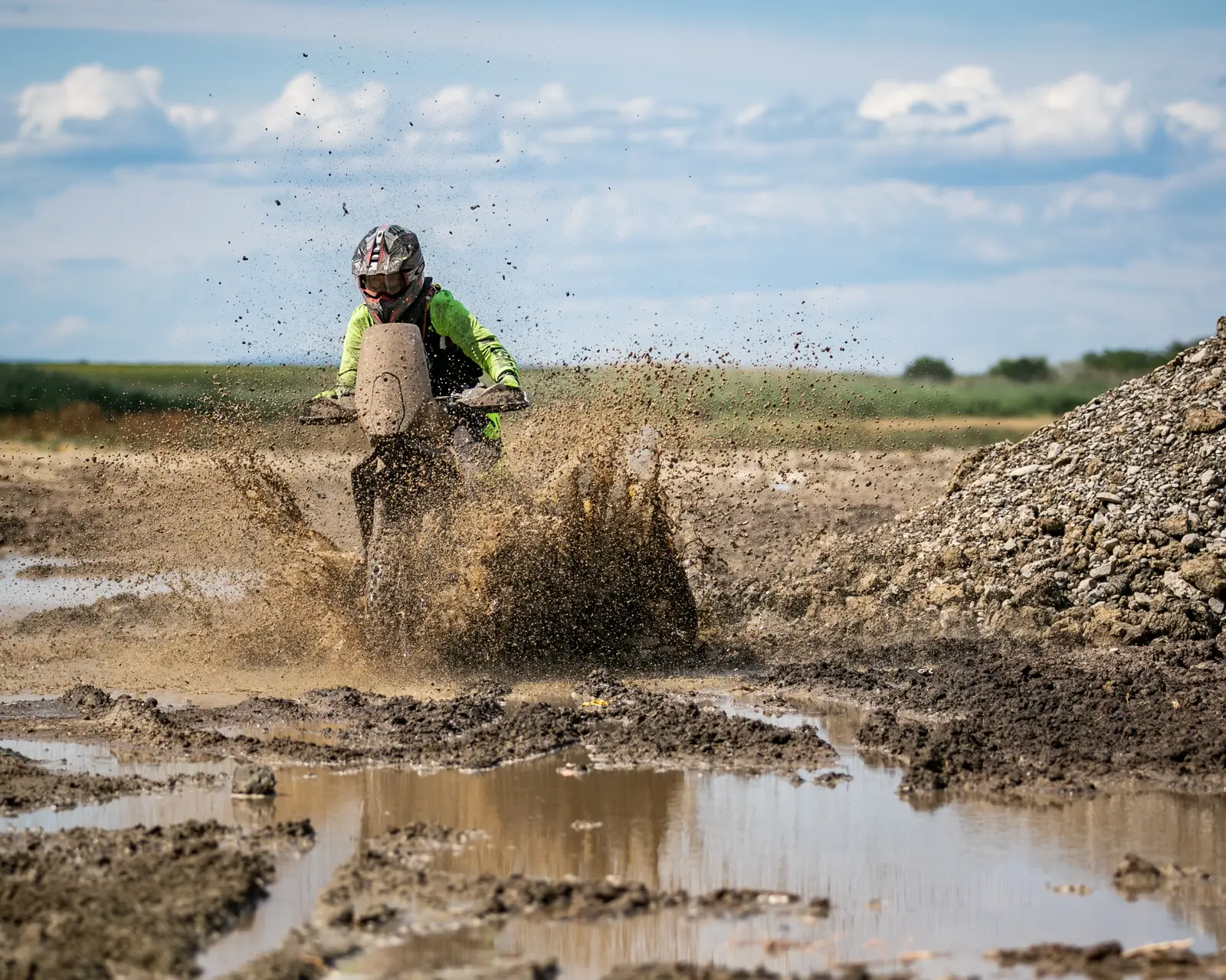 Blasting head-on through a mud hole, dirt spraying in all directions
